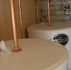 Two white water tanks with copper pipes in a utility room, one labeled TEMPEST, against a brick wall.