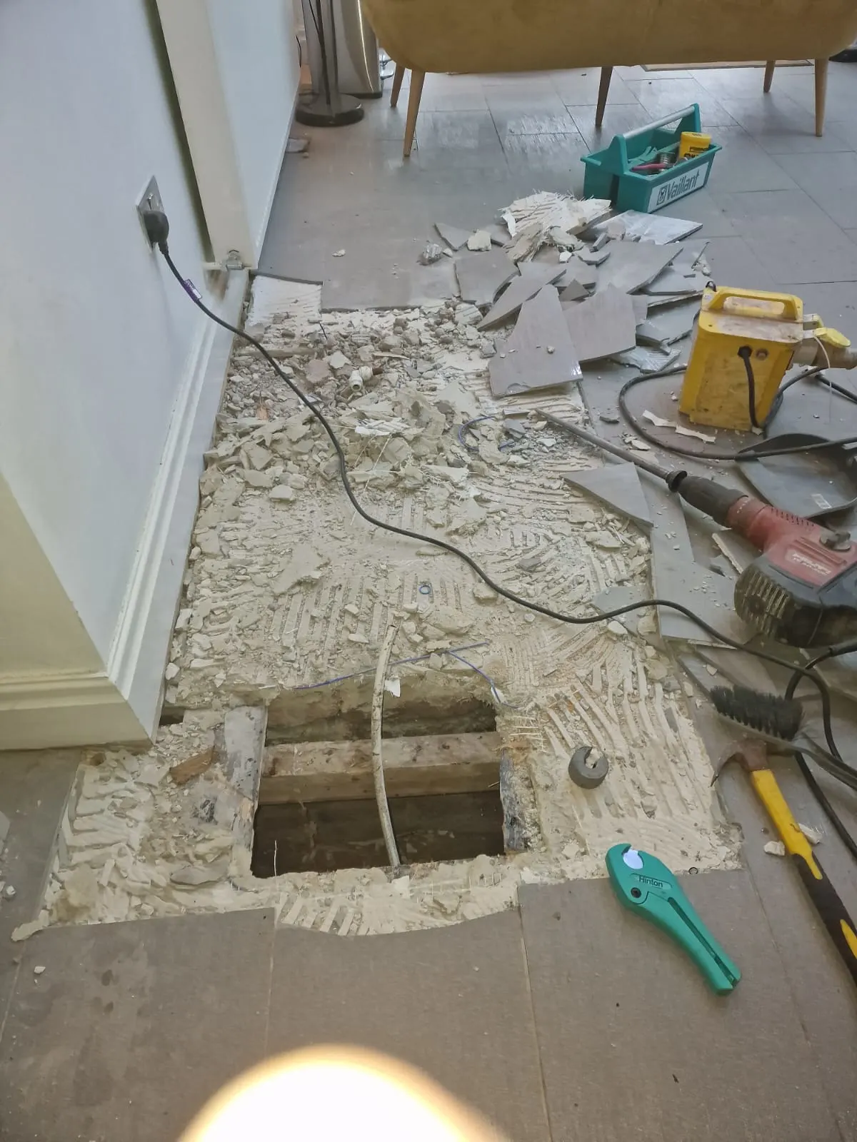 Another shot of the kitchen, but the tiles have been pulled up on the floor exposed with a hole leading into the basement.