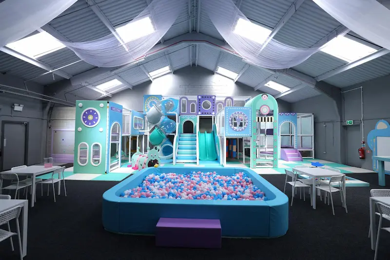 Large pastel colour plastic ball pool in the foreground in the background a large play area