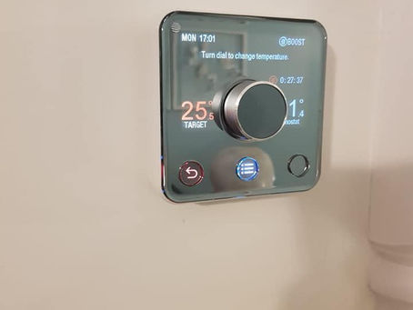 A digital thermostat displays 25°C target and 21°C current temperature on a wall. It shows "Turn dial to change temperature" with a sleek design.