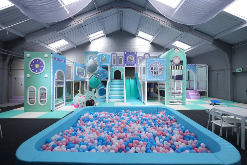 Large pastel colour plastic ball pool in the foreground in the background a large play area