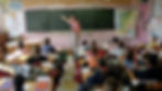 Teacher standing at a chalkboard in the front of the classroom
