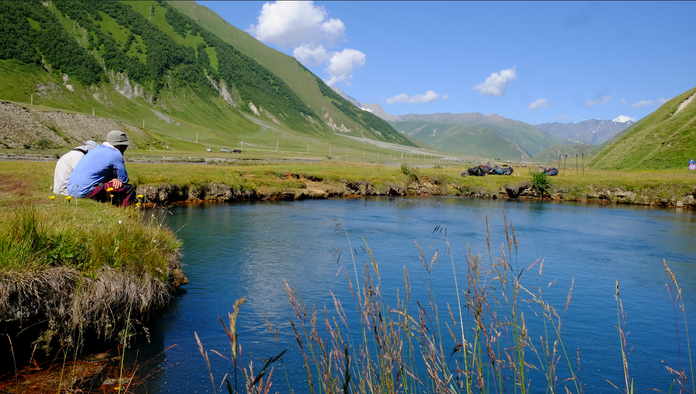 Two guys sitting beside a small pool