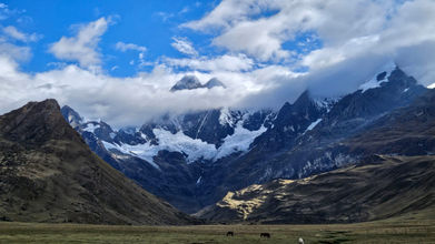 At the bottom a green grass, in the middle a mountains ridge and from above blue sky