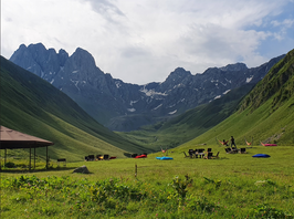 People chilling on a grass land with a mountain view
