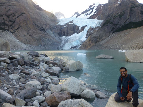 A guy leaning with a lake in the background