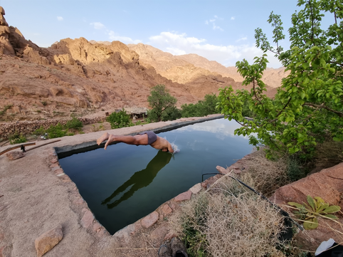 Jumping head first to a pool in the dessert