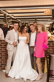 The bride and groom with the parents of the groom smiling