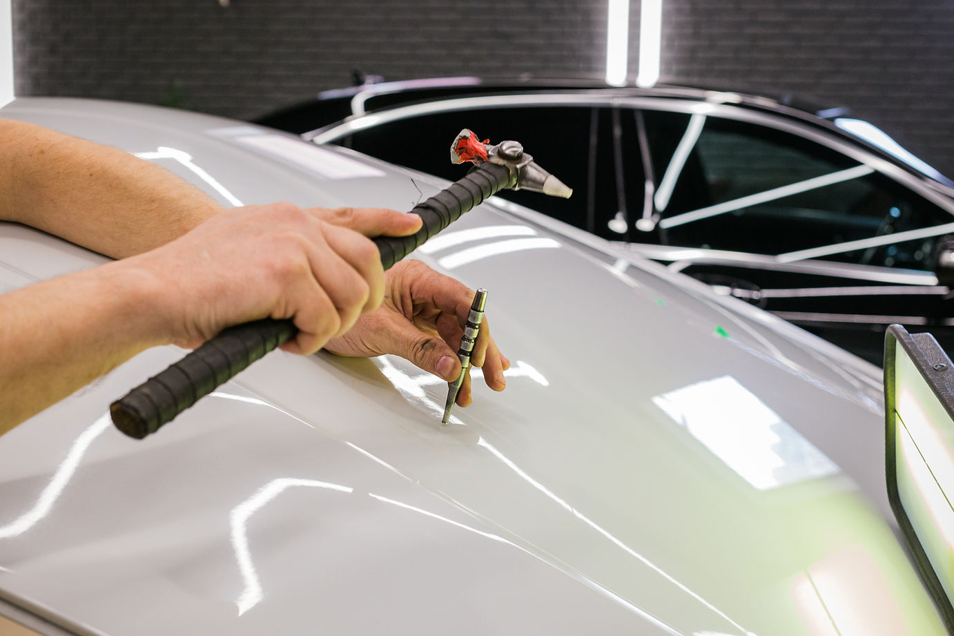 A specialist repairs a dent on the car body without painting. PDR. Process of paintless de