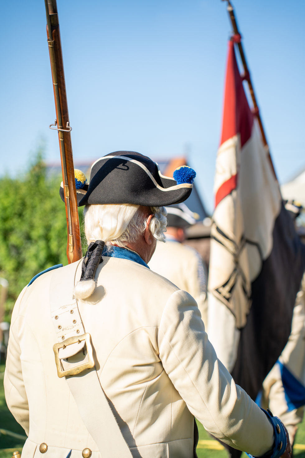 Rückansicht eines uniformierten Mannes mit Gewehr und Schulterriemen.