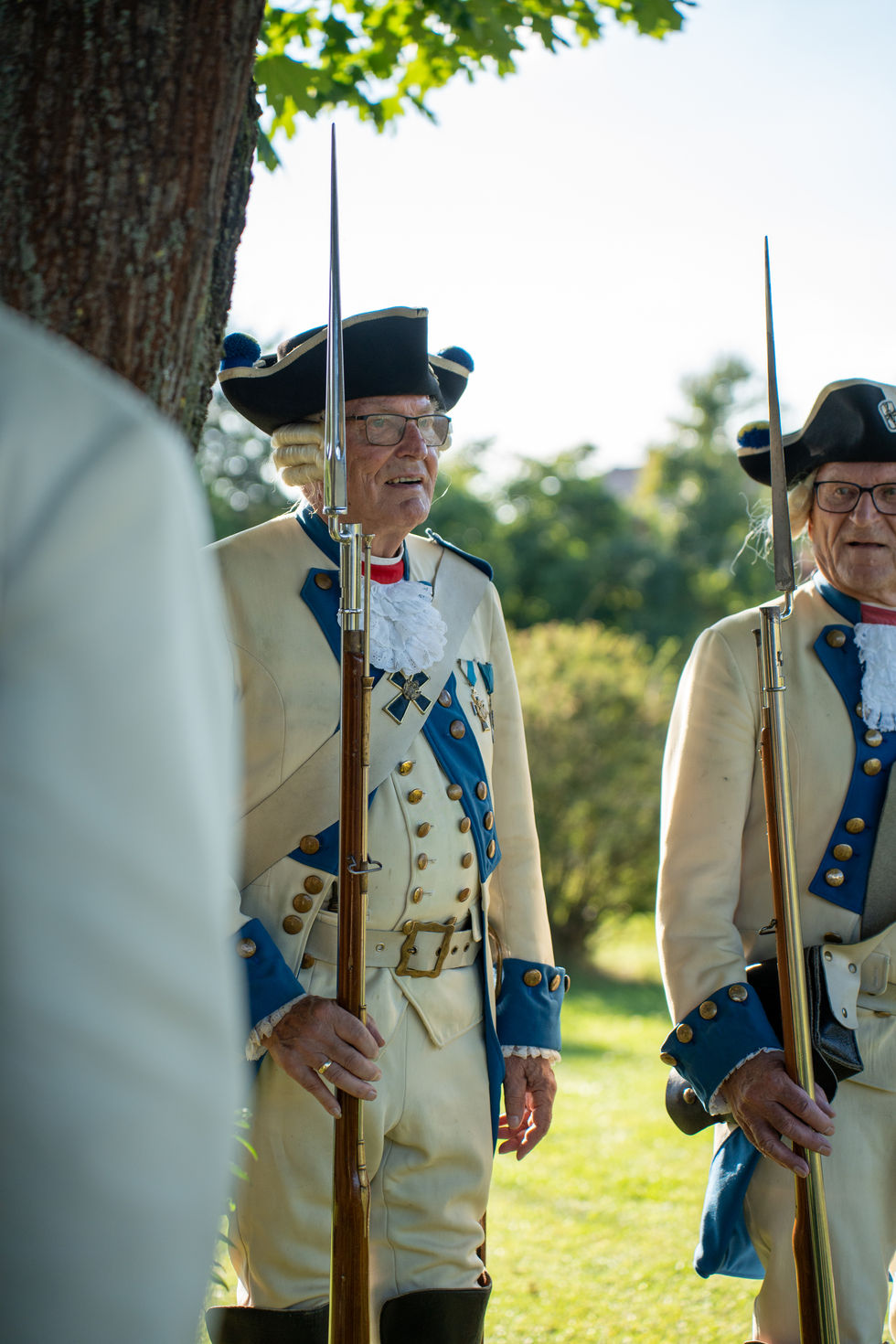 Zwei ältere Männer in Uniform stehen mit langen Gewehren.