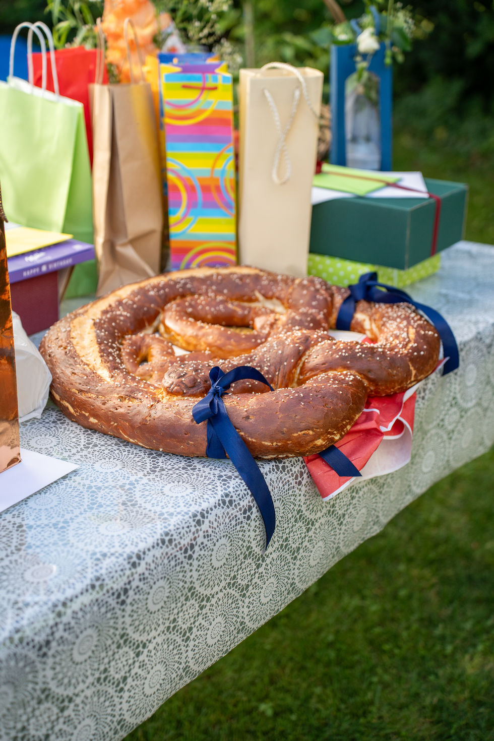 Große Brezel mit blauen Schleifen liegt auf einem Geschenketisch.