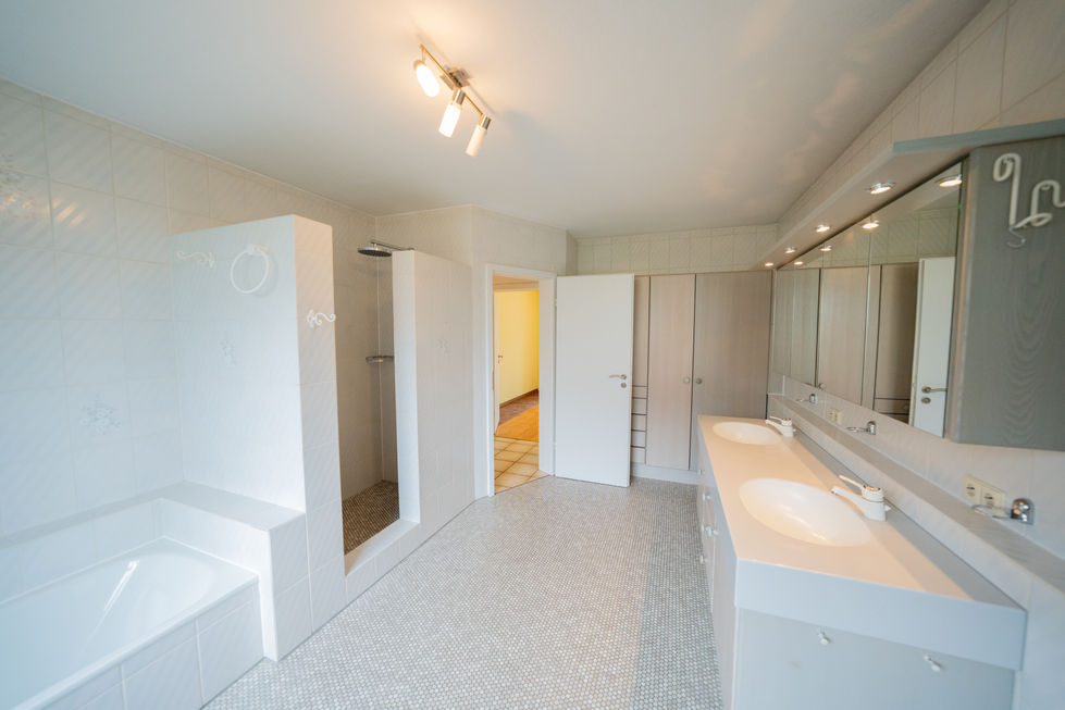 Großes, helles Badezimmer mit Doppelwaschtisch, Badewanne und separater Dusche.