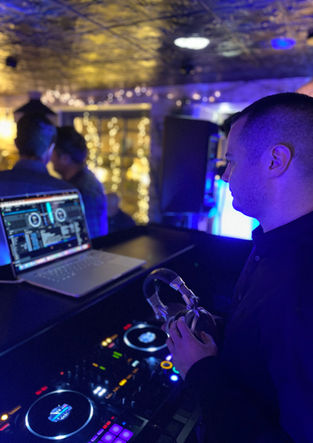 Lead Events DJ is holding headphones and reading the dancefloor, featuring a digital DJ controller and a laptop