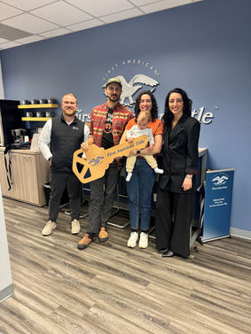 5 people smiling, holding key sign.