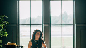 Woman at desk smiling in front of large windows