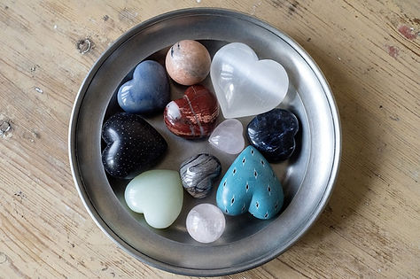 collection of crystal hearts and mini spheres in a metal dish on wooden table