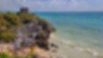 The image captures the natural beauty of the Caribbean coast and the historical richness of the Mayan ruins in Tulum, set against what appears to be a cliff.