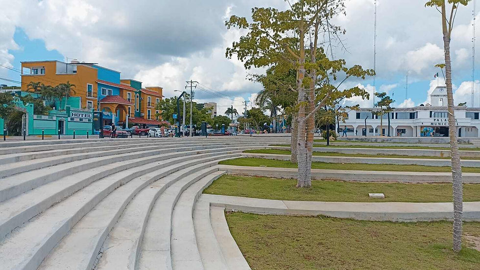 The image shows a sunny public square with concrete steps, featuring the Municipal Palace of Playa del Carmen in the background alongside Hotel Jabines.