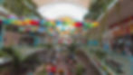 In this image, you can see the cheerful decoration of the plaza from the second floor, with a beautiful garden featuring chairs and many colorful umbrellas hanging from the ceiling.