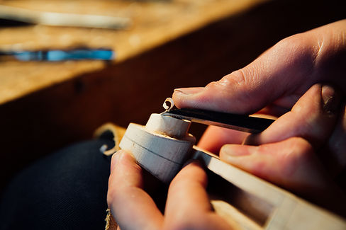 Artisan's hands carefully shaping a delicate piece of jewelry with tools.