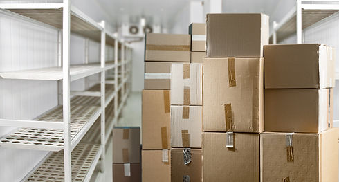 Stacked cardboard boxes in a cold storage room with empty shelves