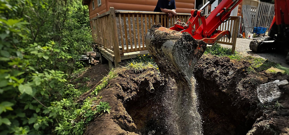 Red excavator digging a hole for septic repairs near a cabin.