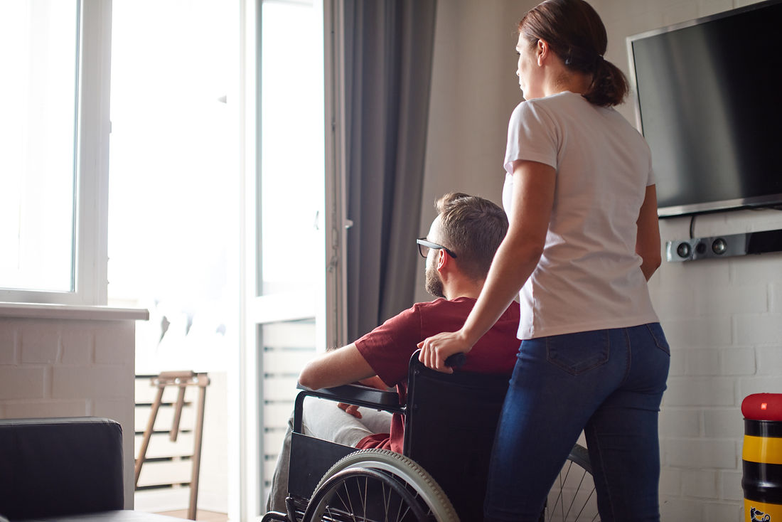 Caregiver assisting man in wheelchair at home