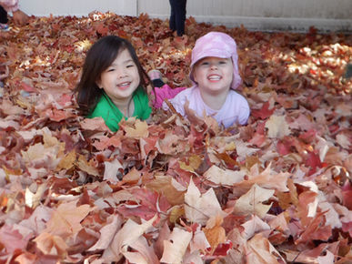 Two happy children playing in a pile of colorful autumn leaves