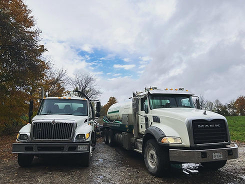 Two white Mack service trucks parked outdoors.