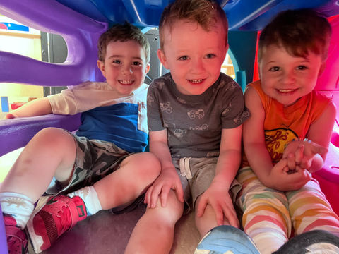Three young boys smiling while playing together, happy kids.