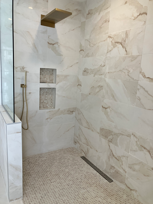 Modern walk-in shower with marble tiles and gold fixtures