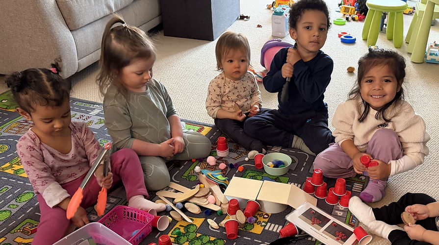 Five diverse young children playing with colorful toys on a patterned rug.
