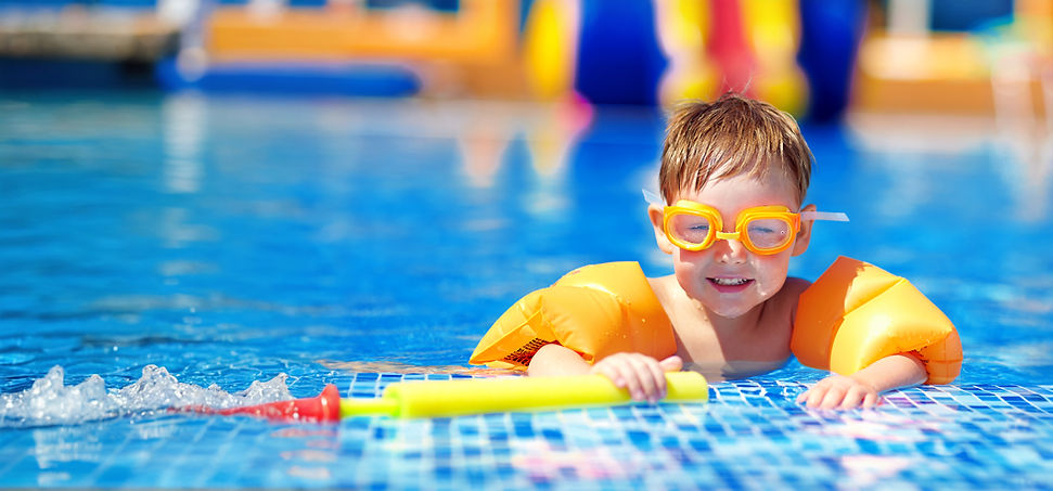 Young child with goggles and floaties in a swimming pool.