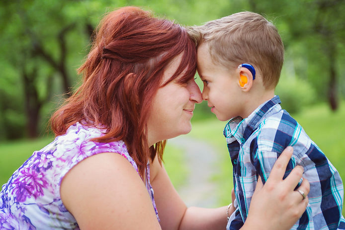 Woman and boy with hearing aid share a tender moment