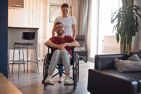 Woman assisting smiling man in wheelchair at home
