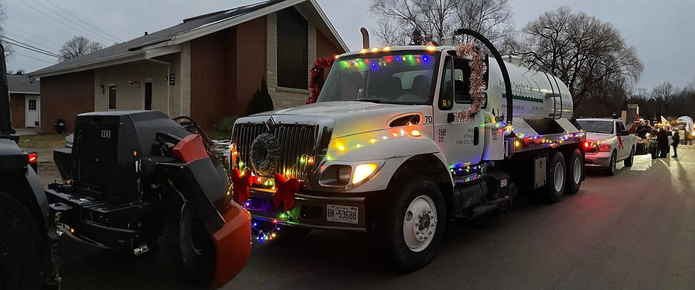 A white septic truck decorated with Christmas lights in a parade