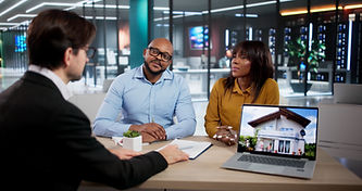 Couple discusses finances with advisor, house on laptop