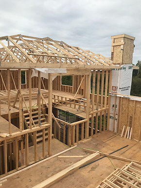 Wooden house frame under construction showing roof trusses.