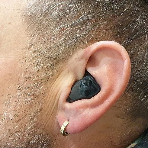 Person wearing a black In-the-Ear (ITE) hearing aid.