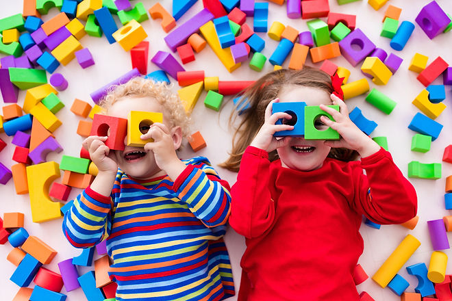 Two happy children playing with vibrant building blocks, smiling brightly.