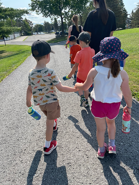 Children walking on a path holding hands and walking with an adult
