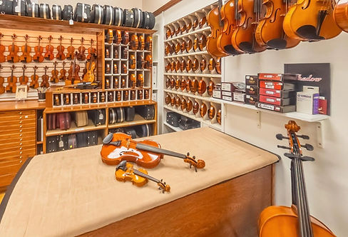 Violin store interior with numerous string instruments, violins, and cellos.