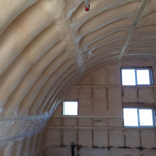 Spray foam insulation covering an arched ceiling and walls.