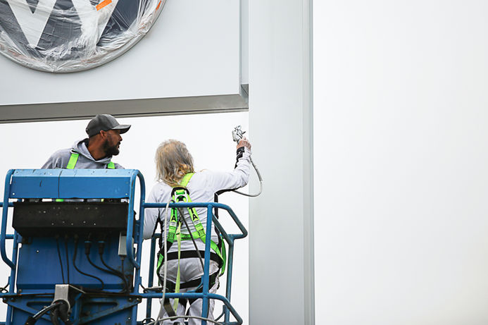 Commercial painting team using a lift to spray paint a building exterior.
