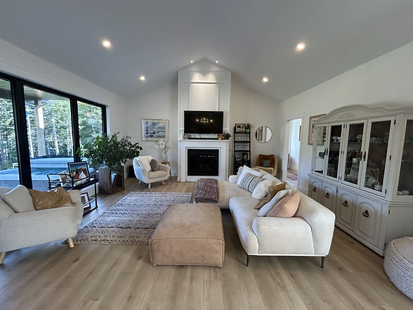 Modern living room with light furniture, fireplace, and large windows