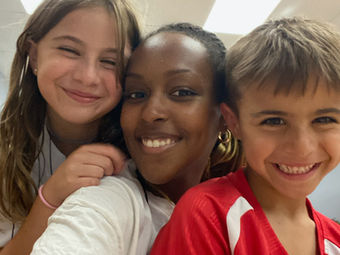 Young woman with two smiling children, a girl and a boy, happily posing.