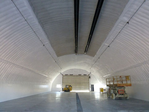 Spacious arched building with a loader and scissor lift