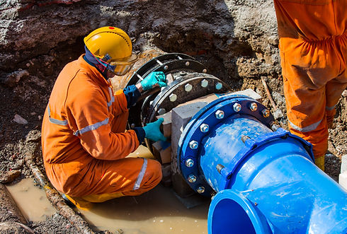 Trabalhador consertando tubo de água azul em canteiro de obras.
