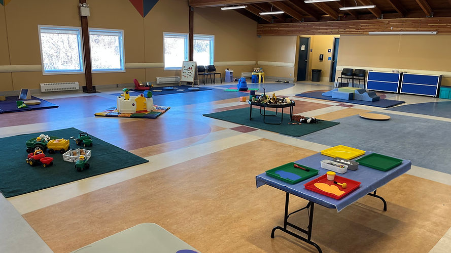 Large room arranged with colorful play areas and activities for children.